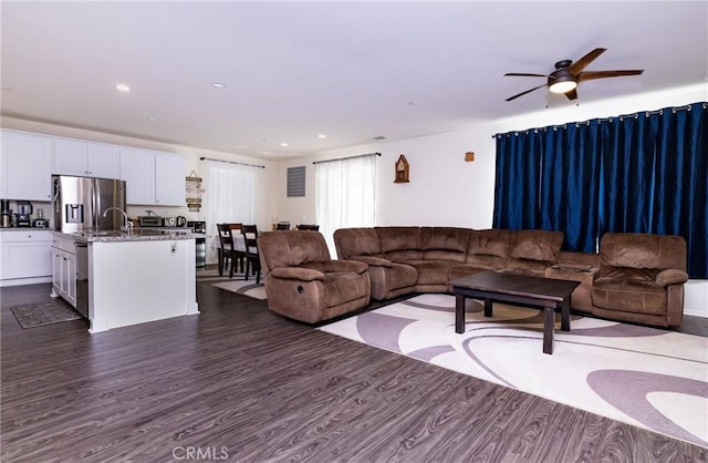 living room with ceiling fan and dark hardwood / wood-style flooring