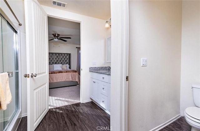 bathroom with ceiling fan, hardwood / wood-style floors, vanity, a shower with shower door, and toilet