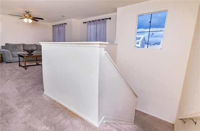 corridor featuring ceiling fan and carpet