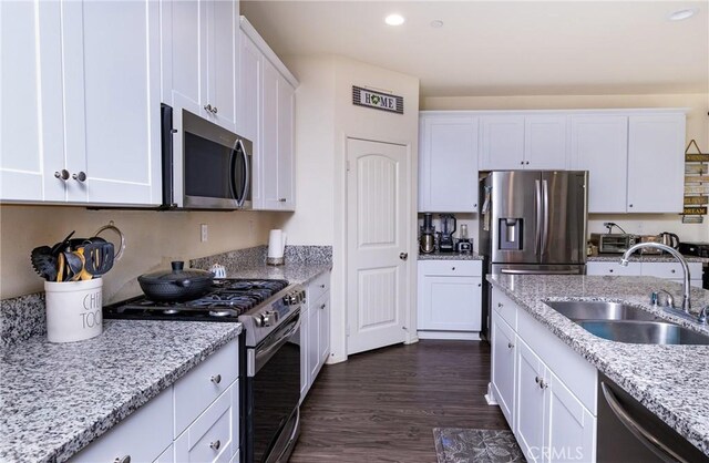 kitchen featuring white cabinetry, stainless steel appliances, light stone countertops, and sink