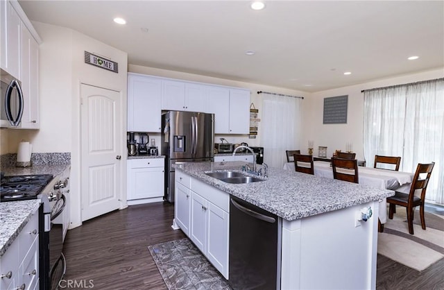 kitchen with stainless steel appliances, a kitchen island with sink, sink, and white cabinets