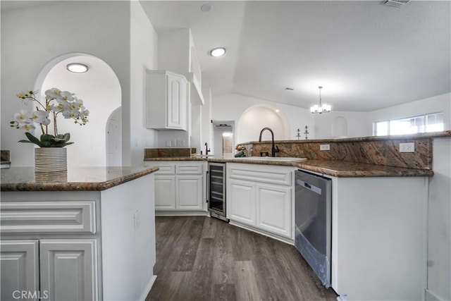 kitchen with sink, dishwasher, dark stone countertops, white cabinets, and decorative light fixtures