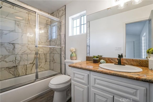 full bathroom with toilet, vanity, shower / bath combination with glass door, and hardwood / wood-style flooring