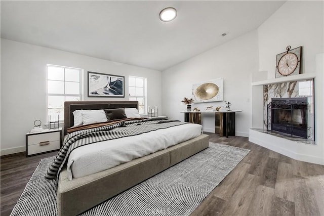 bedroom with lofted ceiling, wood-type flooring, and a tile fireplace