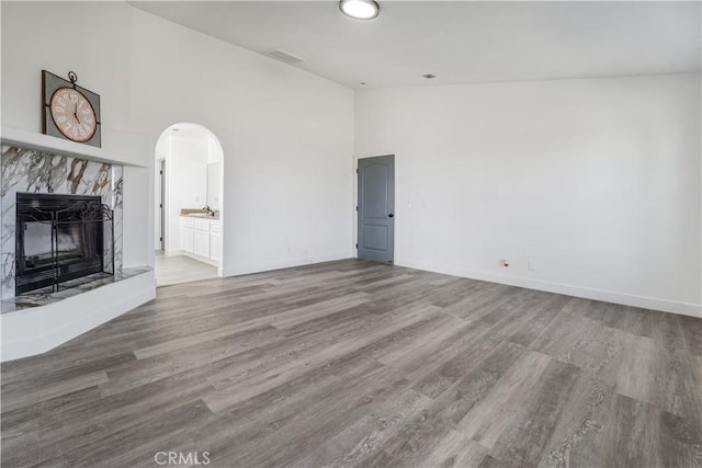 unfurnished living room featuring hardwood / wood-style flooring, a premium fireplace, and high vaulted ceiling