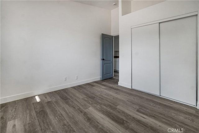 unfurnished bedroom with dark wood-type flooring and a closet