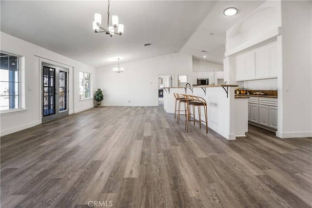 unfurnished living room featuring dark wood-type flooring, lofted ceiling, and a notable chandelier