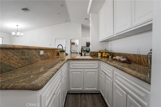 kitchen featuring white cabinetry, kitchen peninsula, and dark stone countertops