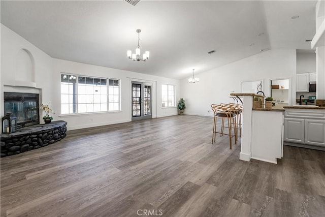 living room featuring an inviting chandelier, dark hardwood / wood-style floors, sink, and vaulted ceiling