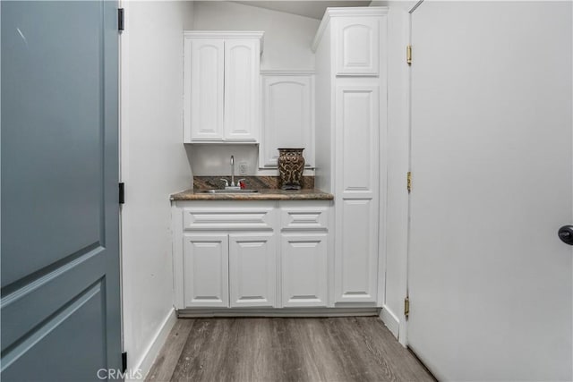 interior space featuring white cabinetry, sink, dark hardwood / wood-style floors, and dark stone counters