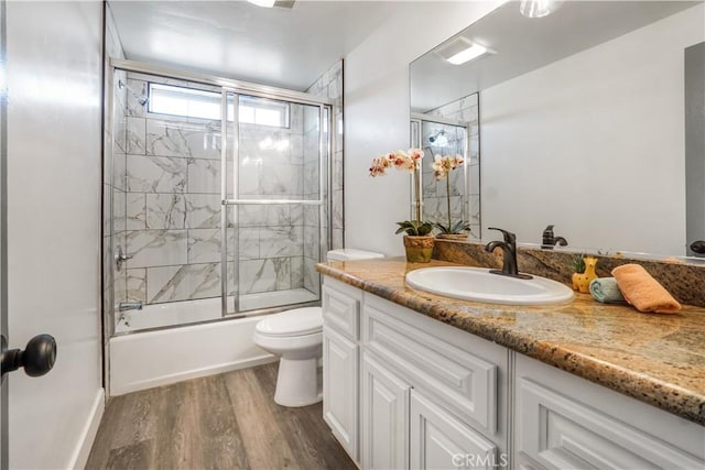 full bathroom with hardwood / wood-style flooring, enclosed tub / shower combo, vanity, and toilet