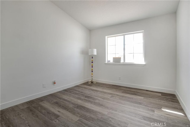 spare room with hardwood / wood-style flooring and lofted ceiling