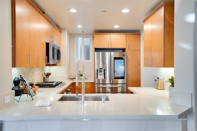 kitchen with stainless steel appliances, kitchen peninsula, decorative backsplash, and light brown cabinets