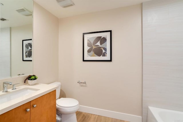 bathroom featuring hardwood / wood-style flooring, vanity, a tub, and toilet