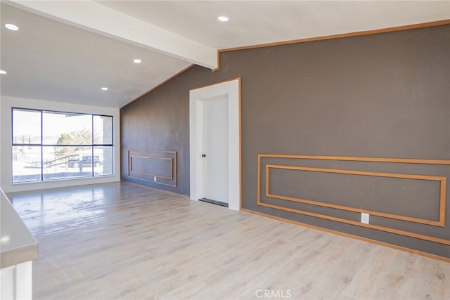 empty room with lofted ceiling with beams and light wood-type flooring