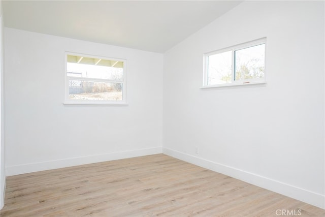 unfurnished room featuring lofted ceiling and light hardwood / wood-style flooring