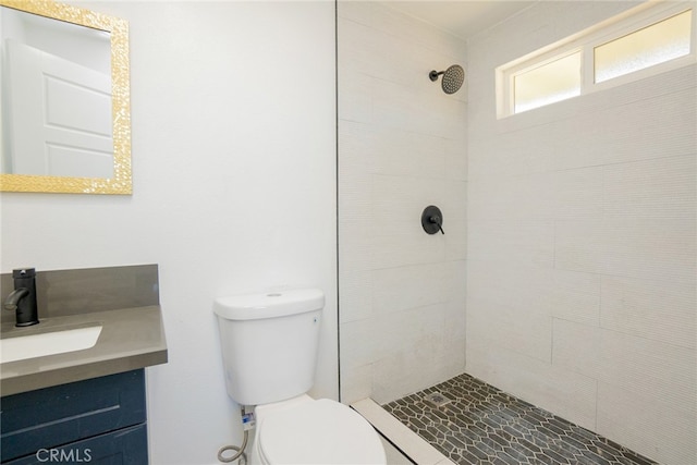 bathroom with vanity, a tile shower, and toilet