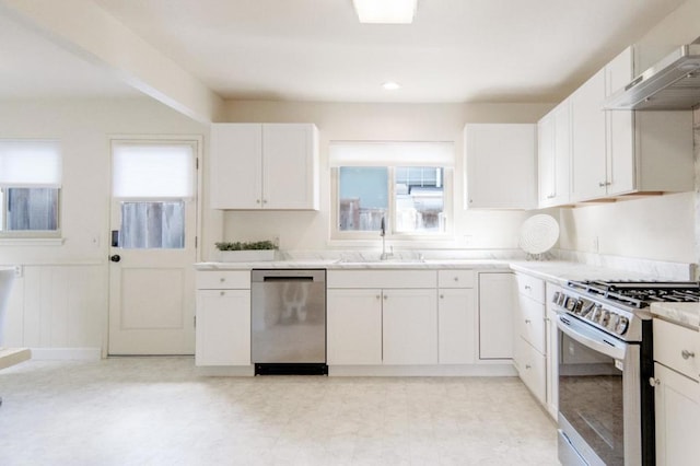 kitchen with stainless steel appliances, sink, exhaust hood, and white cabinets