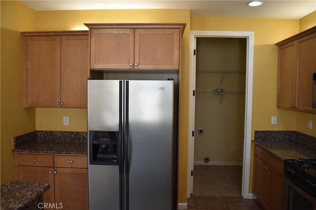 kitchen featuring tile patterned flooring, appliances with stainless steel finishes, and dark stone countertops