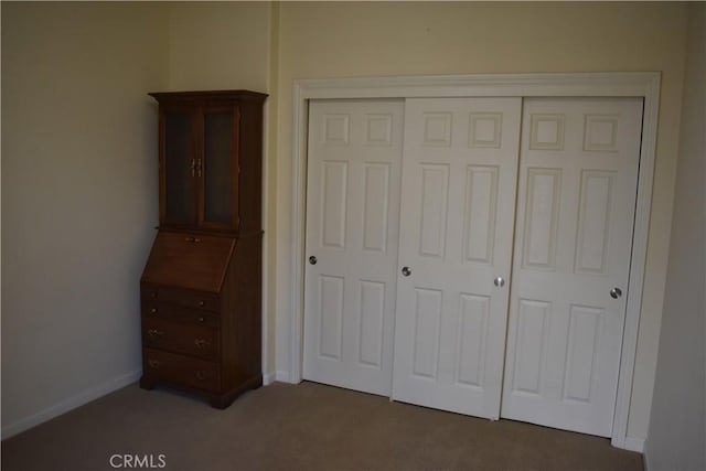 unfurnished bedroom with dark carpet and a closet