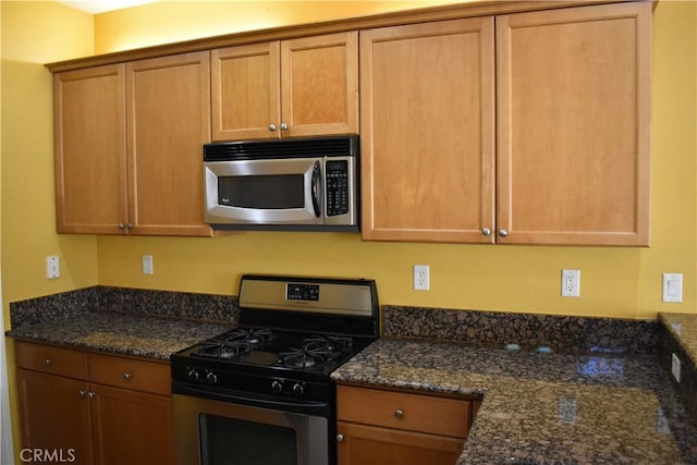 kitchen with stainless steel appliances and dark stone countertops