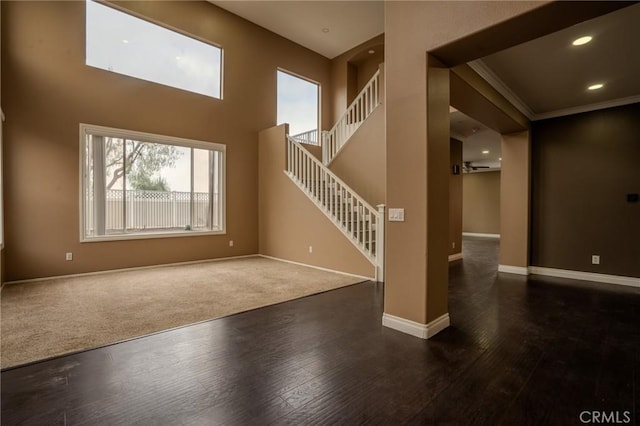 unfurnished living room featuring ornamental molding, dark hardwood / wood-style floors, and a high ceiling