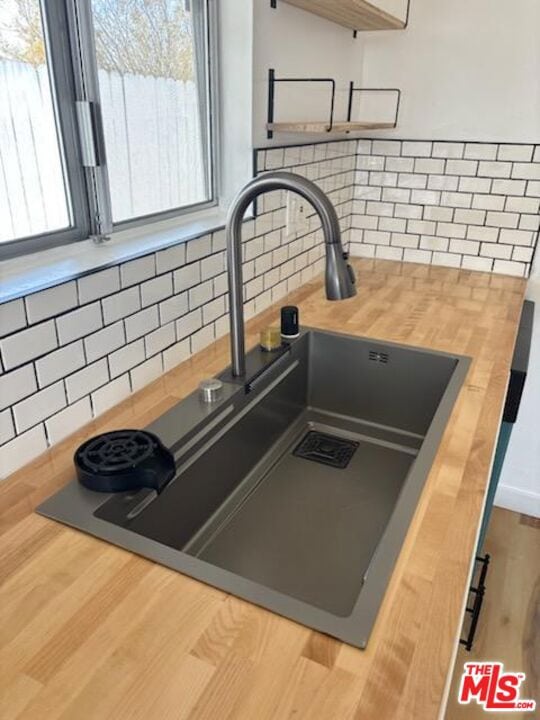 details featuring wood counters, sink, and tasteful backsplash