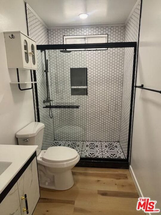 bathroom with hardwood / wood-style flooring, vanity, toilet, and a shower