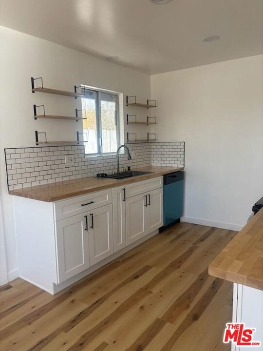 kitchen with wooden counters, dishwasher, white cabinets, light hardwood / wood-style floors, and backsplash