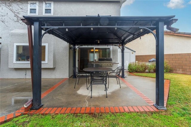 view of patio / terrace featuring a gazebo, outdoor dining space, and fence