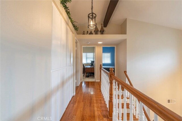 hall featuring lofted ceiling with beams, visible vents, an upstairs landing, and wood finished floors