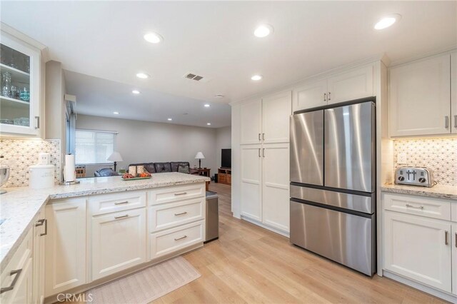 kitchen featuring visible vents, light wood-type flooring, a peninsula, freestanding refrigerator, and white cabinets