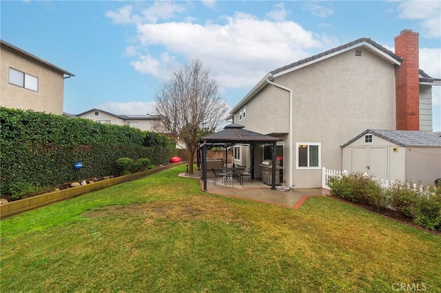 back of house with a gazebo, stucco siding, a fenced backyard, a yard, and a patio