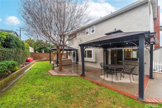 back of house featuring stucco siding, a patio, a fenced backyard, a gazebo, and a yard