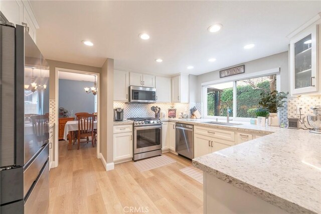 kitchen featuring a sink, tasteful backsplash, appliances with stainless steel finishes, and light wood-style flooring