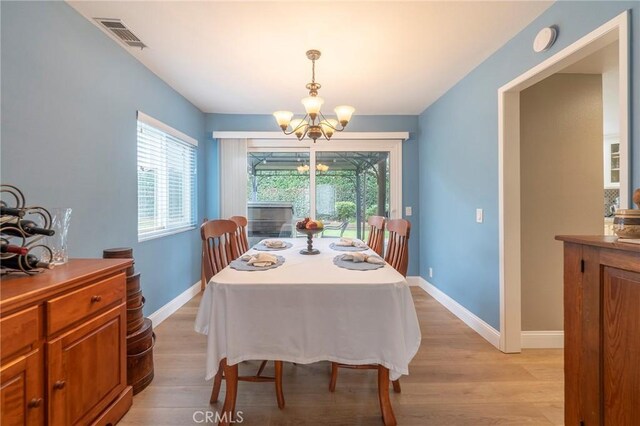 dining area featuring visible vents, baseboards, light wood-style floors, and an inviting chandelier