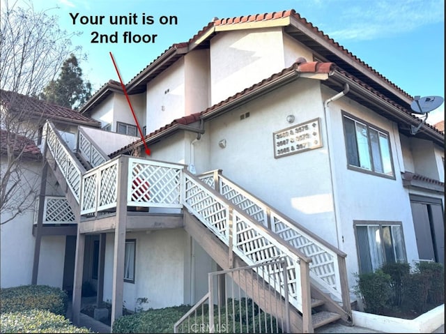 view of side of property featuring stairway and stucco siding