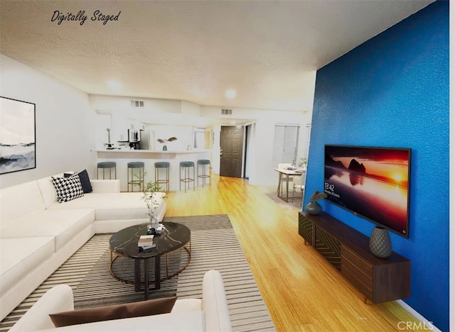 living room with a textured ceiling, visible vents, and wood finished floors