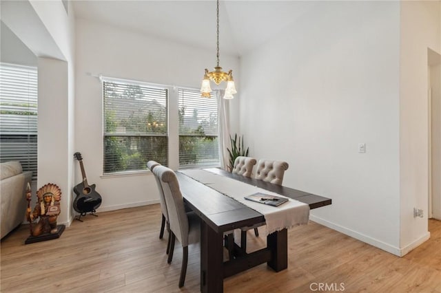 dining area featuring lofted ceiling, light hardwood / wood-style floors, and a notable chandelier