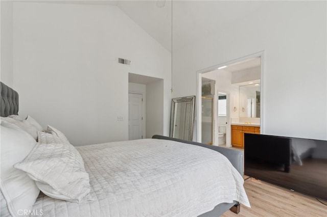 bedroom featuring ensuite bathroom, high vaulted ceiling, and light hardwood / wood-style flooring