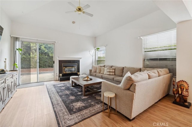 living room with lofted ceiling, a fireplace, light hardwood / wood-style floors, and ceiling fan