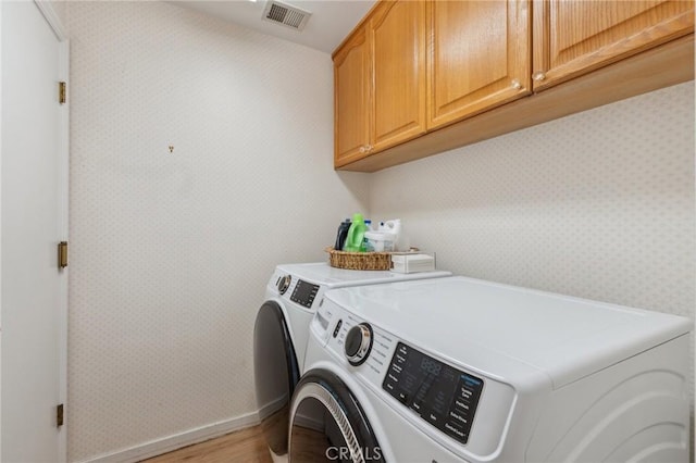 laundry room with cabinets, hardwood / wood-style flooring, and independent washer and dryer