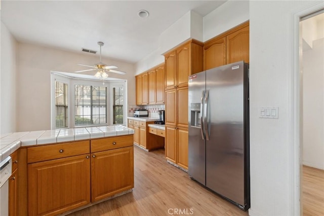 kitchen featuring light hardwood / wood-style flooring, tile counters, dishwasher, and stainless steel refrigerator with ice dispenser