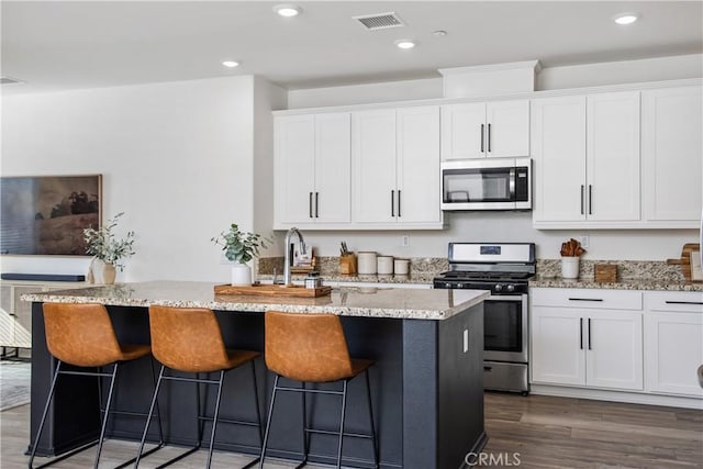 30219 Old Mill Rd, Menifee, CA 92584 - kitchen with appliances with stainless steel finishes, light stone counters, white cabinetry, wood finished floors, and recessed lighting