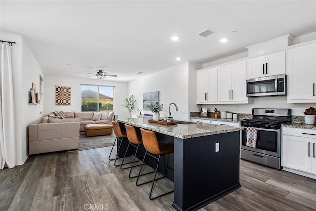 30219 Old Mill Rd, Menifee, CA 92584 - kitchen with stainless steel appliances, a sink, light stone countertops, an island with sink, and white cabinetry