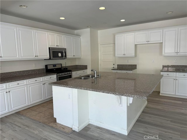 kitchen with white cabinetry, appliances with stainless steel finishes, sink, and a kitchen island with sink