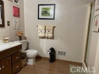 bathroom with vanity, hardwood / wood-style flooring, a shower with door, and toilet