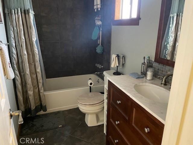 full bathroom featuring shower / bath combination with curtain, decorative backsplash, vanity, toilet, and tile patterned floors