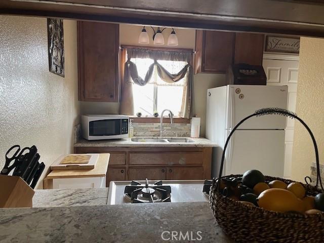 kitchen with light stone counters, sink, and white fridge