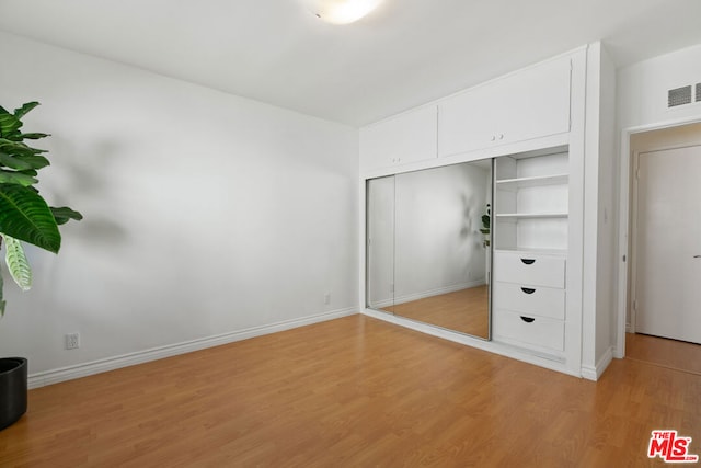 unfurnished bedroom with light wood-type flooring and a closet